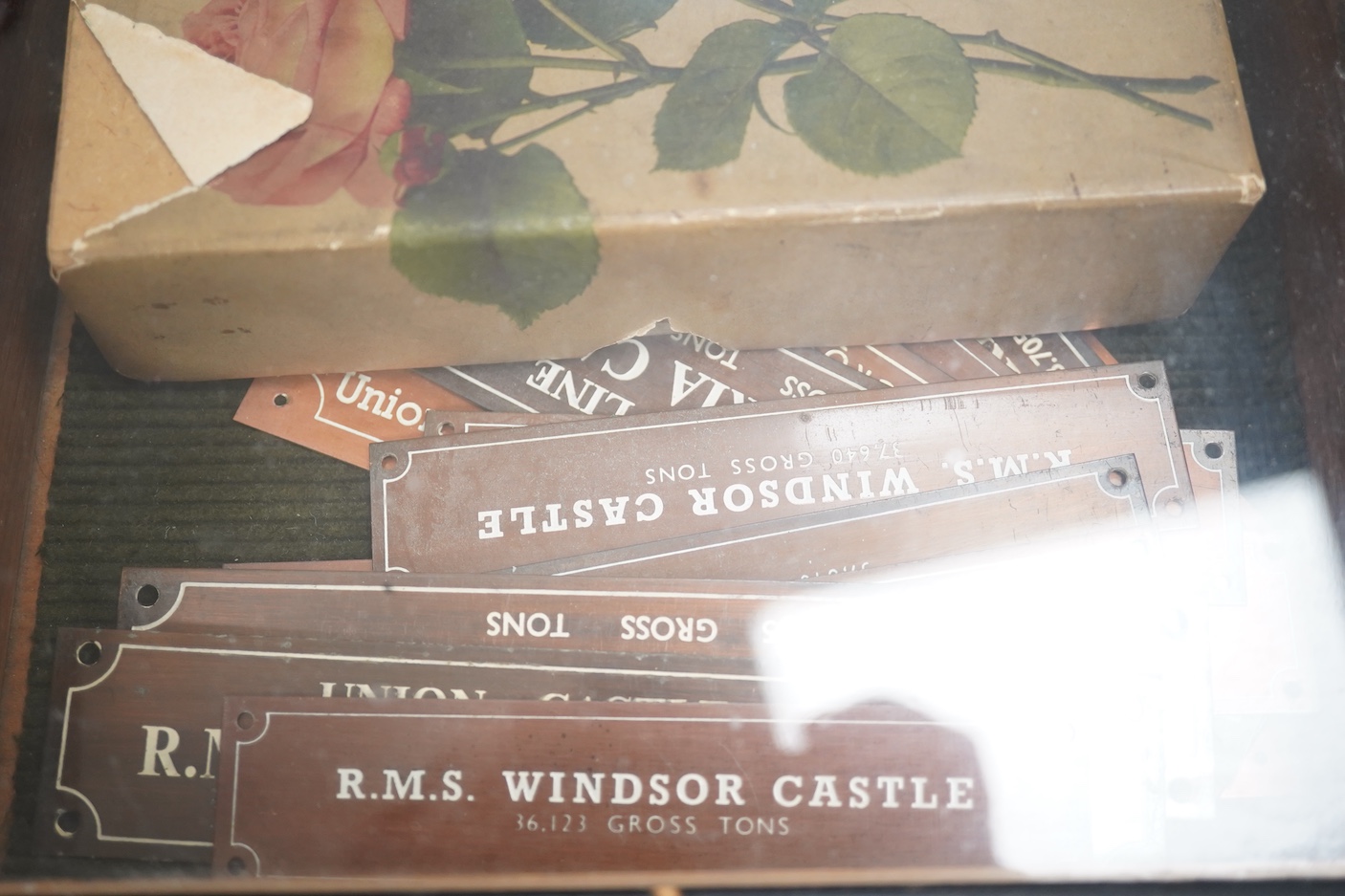 Sundry items comprising a small figured walnut table top collectors cabinet, a display case containing miniature rifles and pistols, a collection of copper and brass miniature RMS nameplates